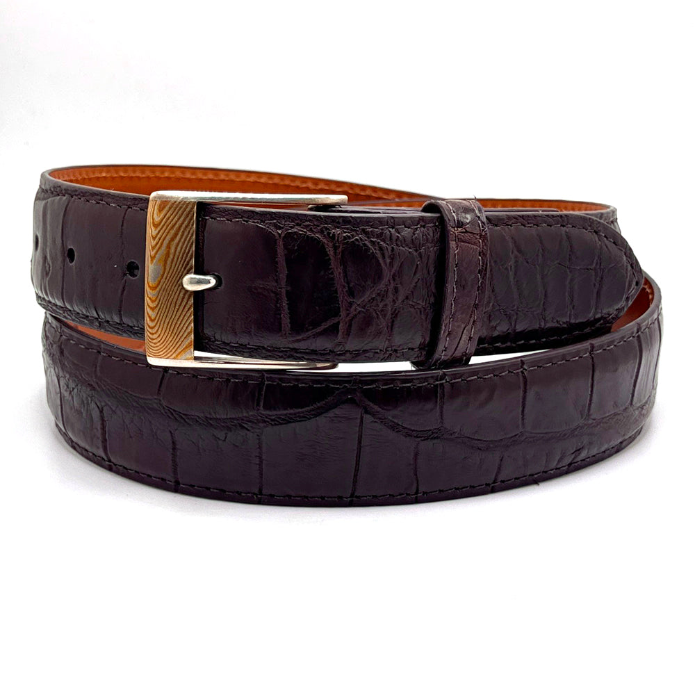 Neil Hunt Mokume-Gane belt buckle shown on a matte brown alligator belt strap.