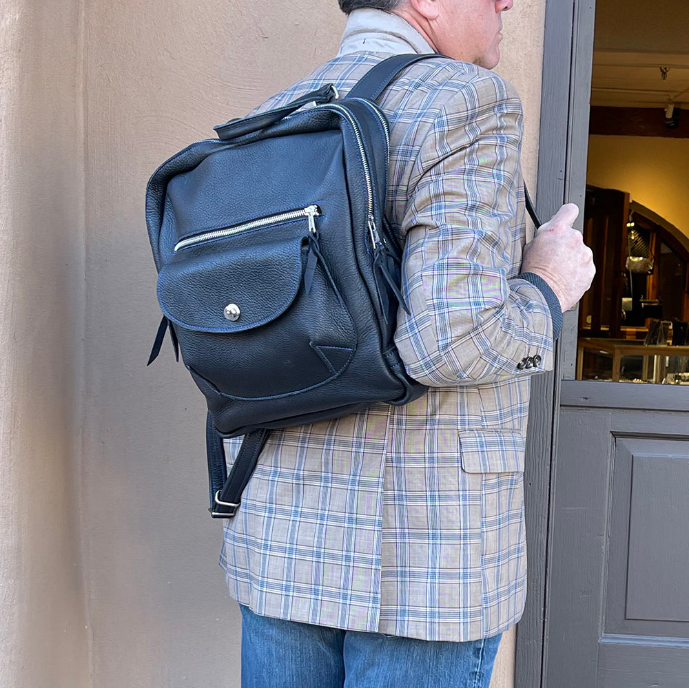 Man carrying black leather backpack over his shoulder. 