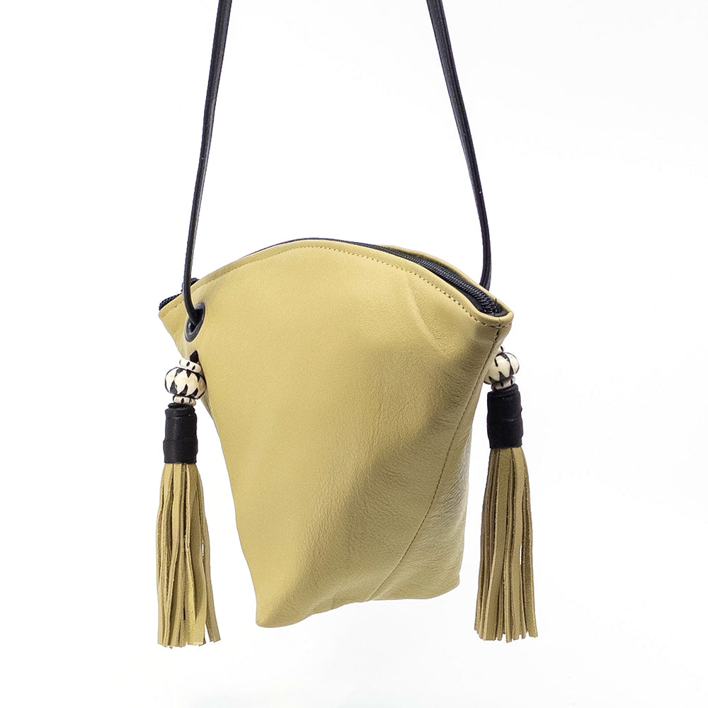 A light yellow leather shoulder bag with a black strap and matching black tassel accents, shown against a plain white background.