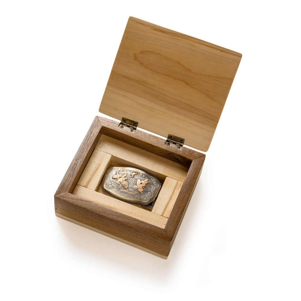 A small rectangular wooden keepsake box with an open lid, shown on a white background. Inside, a Neil Hunt limited edition "Covey of Quail" belt buckle.